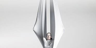 Acrobatic woman sitting in fabric