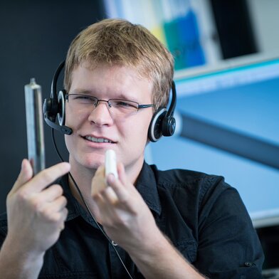 Man on headset holding tube