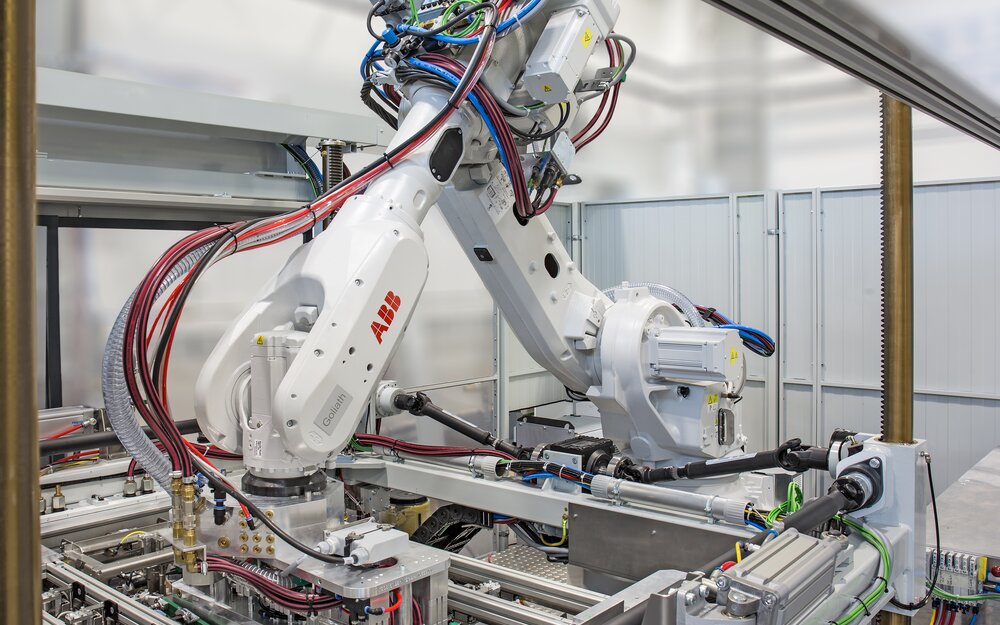 Formstation mit Roboter für Kaschiervorgang und Teilehandling der TBL-Vakuumkaschieranlage.