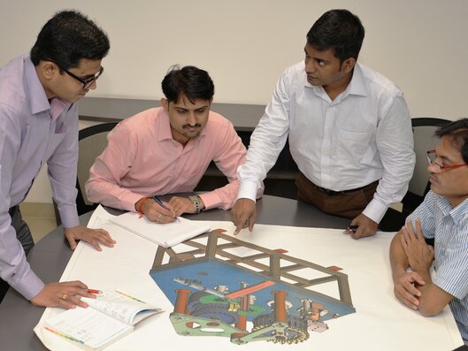 Four men discussing machine drawings