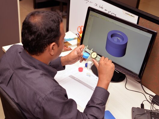 Man comparing plastic cap with computer rendering