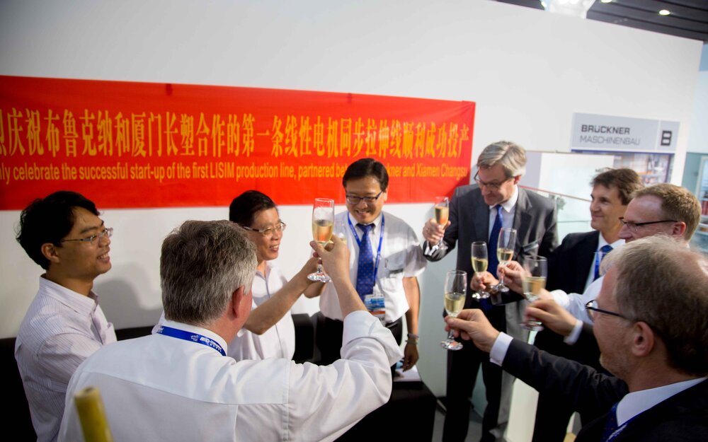 An absolute highlight during the show: celebration at the Brückner booth for the smooth start of the LISIM BOPA line at Xiamen Changsu
