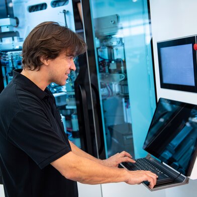Man working on computer from tube machine