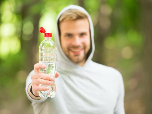 man in a hoodie is holding a plastic bottle