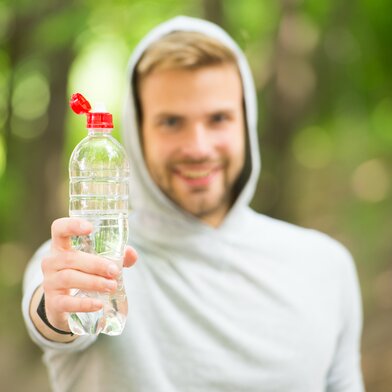 man in a hoodie is holding a plastic bottle